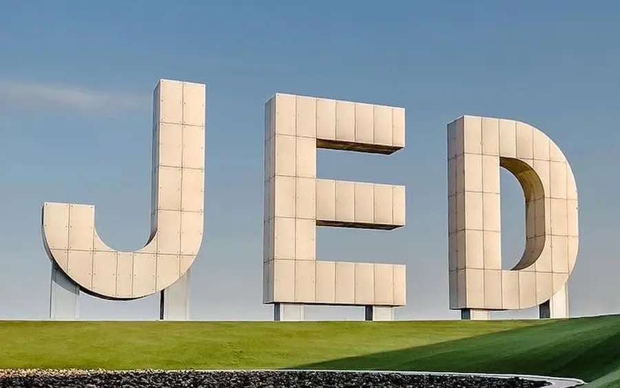 Monumental JED destination sign on a landscaped green hill.